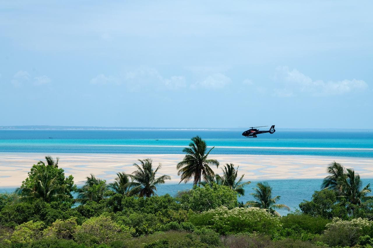 Helicopter flying over the Bazaruto Islands with turquoise waters and palms below